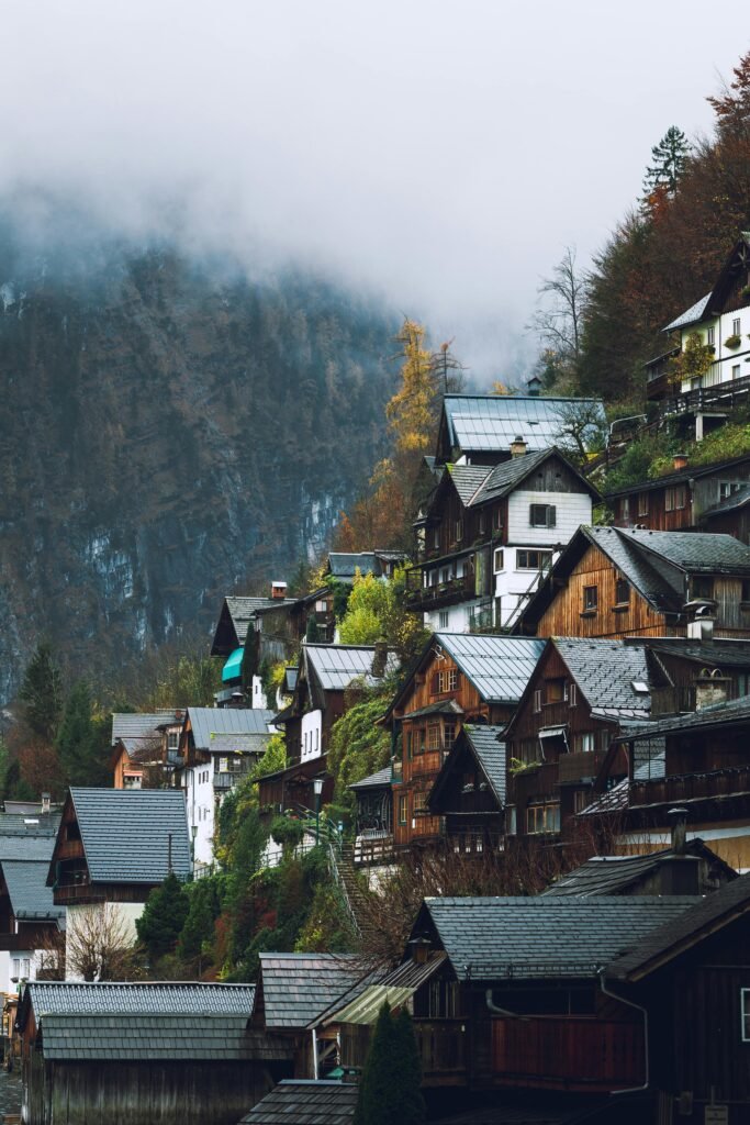 Scenic view of Hallstatt village houses against foggy mountain backdrop, capturing serene alpine beauty.