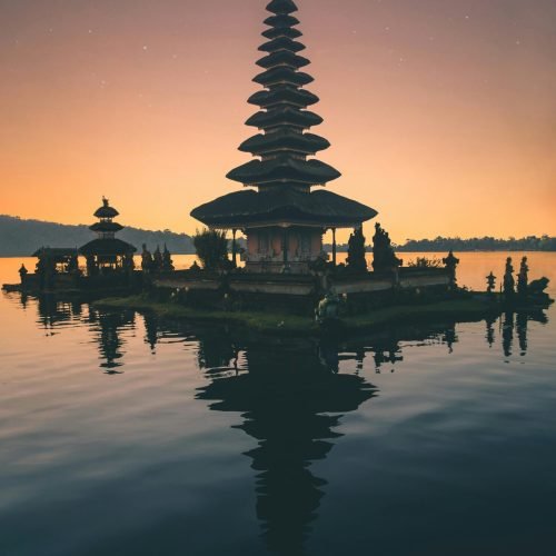 Tranquil reflection of Balinese pagoda on a lake at twilight, capturing spirituality and peace.