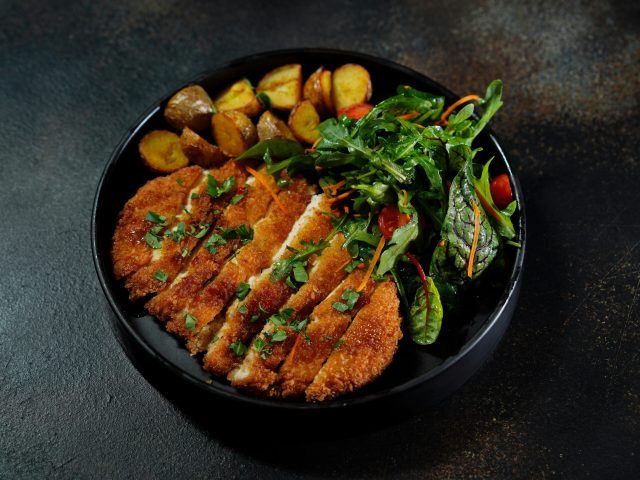 Delicious schnitzel served with roasted potatoes and fresh arugula salad.