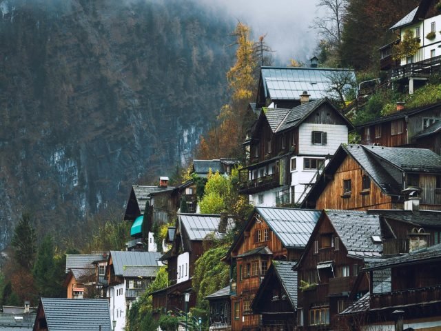 Scenic view of Hallstatt village houses against foggy mountain backdrop, capturing serene alpine beauty.